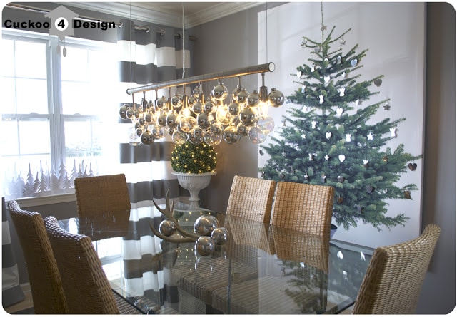 Christmas tree canvas hanging on wall in gray and white dining dining room with silver Christmas balls on chandelier
