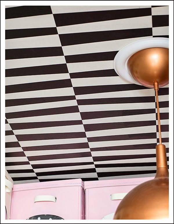 black and white ceiling with copper light fixture and pink storage boxes