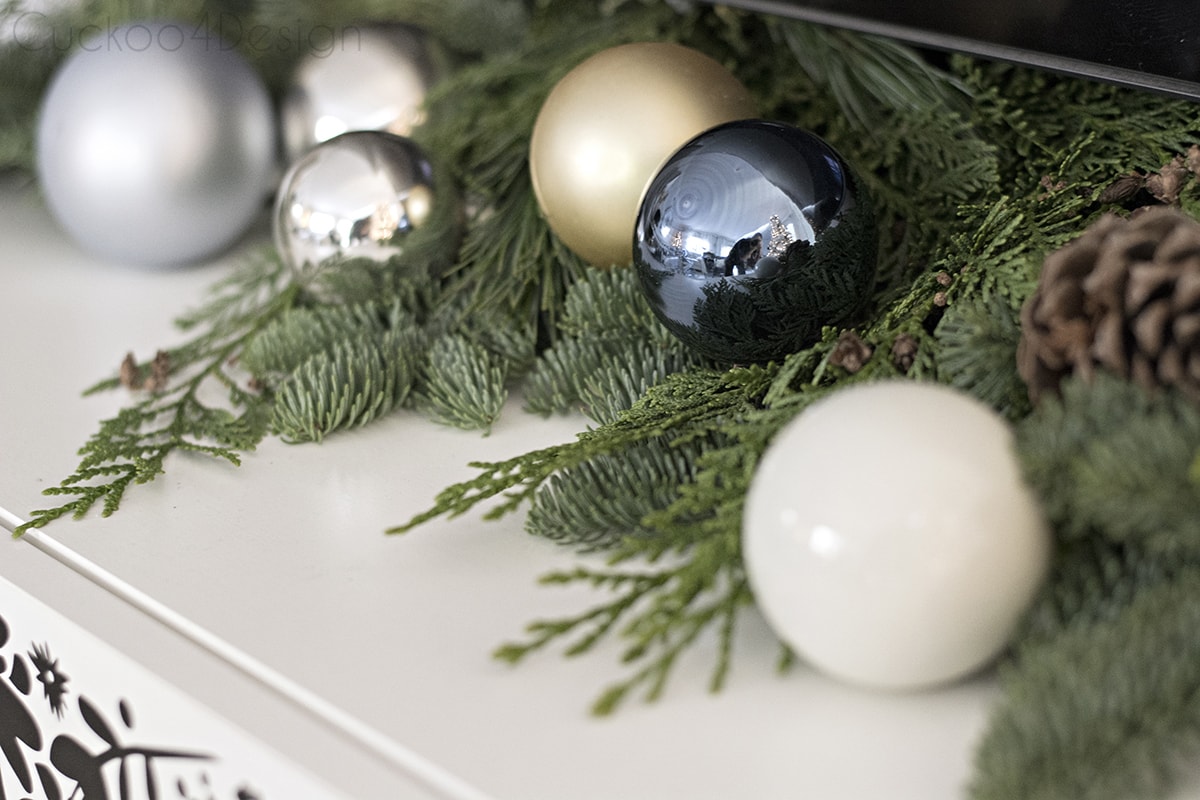 Blue, black and white Christmas ornaments on top of TV cabinet