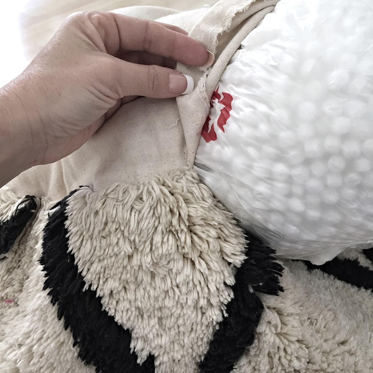 stuffing a closed grocery bag with bean bag filling into pouf opening