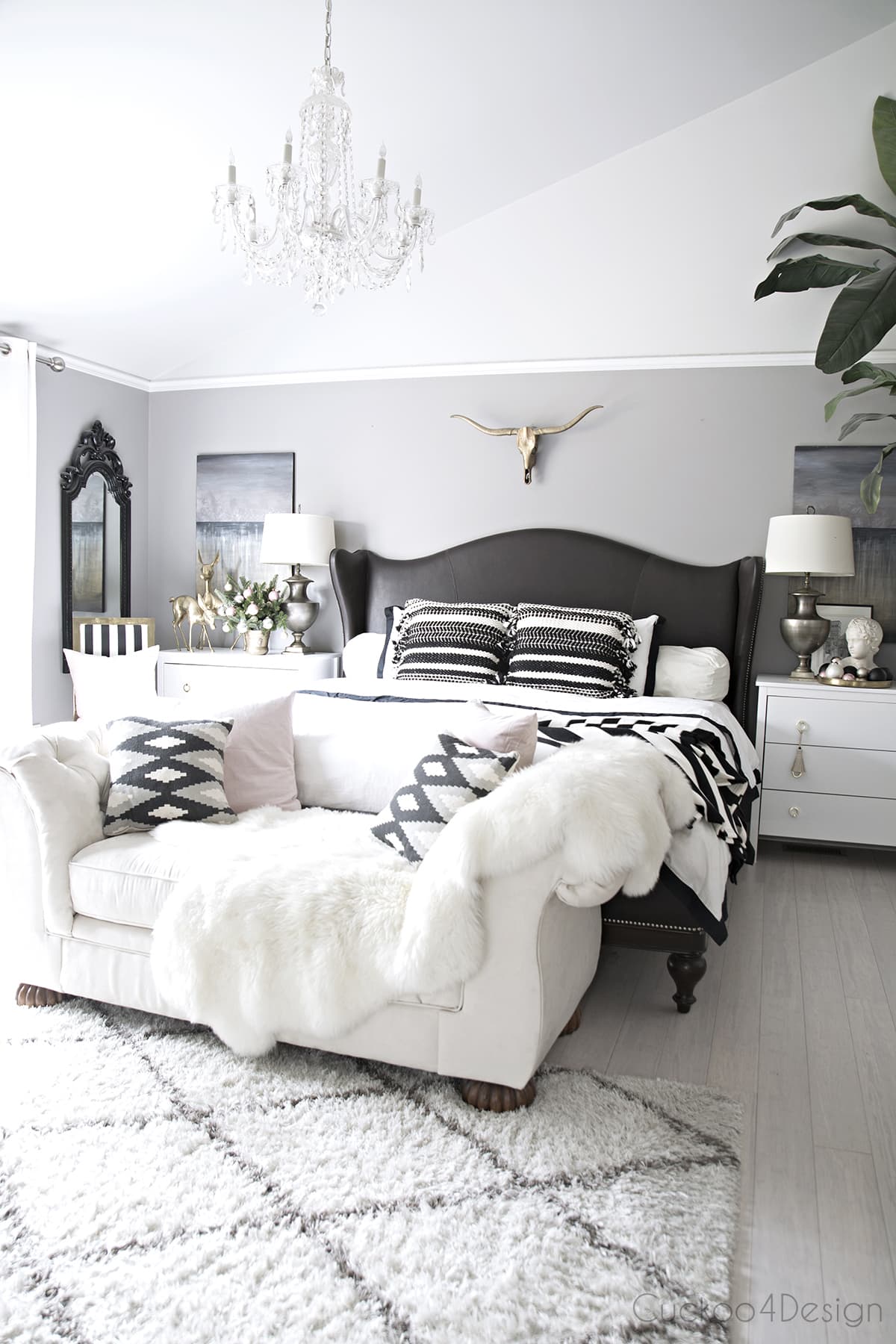 beautiful serene bedroom with leather wingback bed | brass longhorn skull | cathedral ceilings | crystal chandelier | blush and black and white accents 