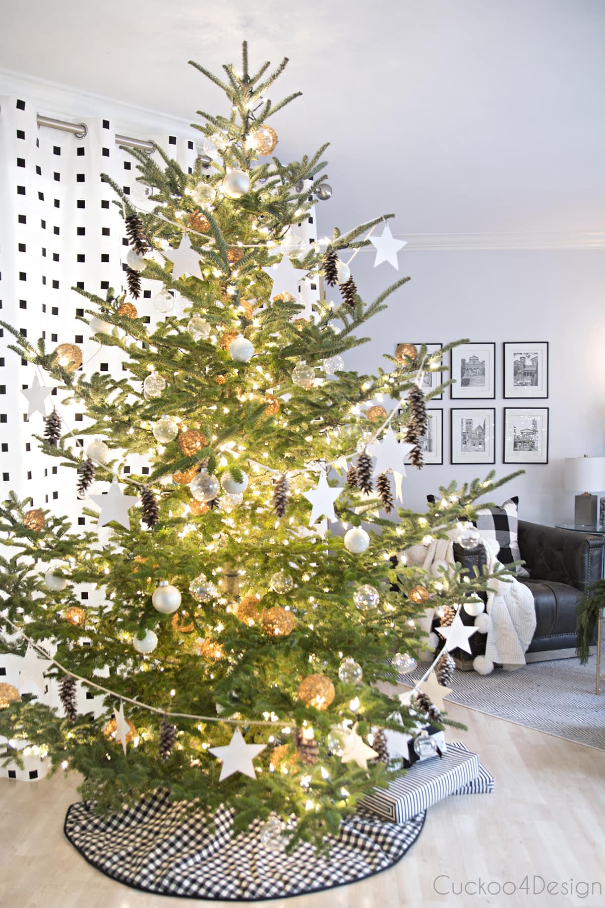Modern European Eclectic Christmas Tree with pinecones, white stars, clear Christmas balls and white Christmas balls on a real untrimmed fir tree | blue, white and black fireplace area with leather swivel chairs