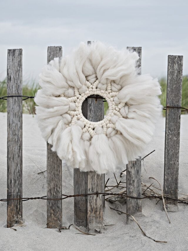 macrame wreath hanging on beach fence