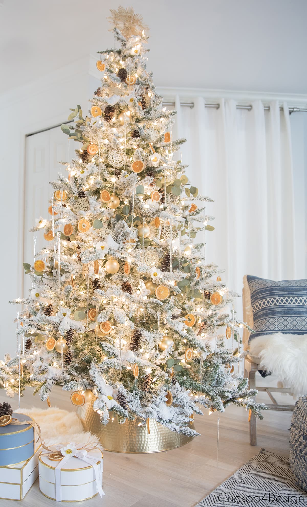 flocked Christmas tree with dried orange slices, eucalyptus branches, straw stars, wooden snowflakes, and pinecones