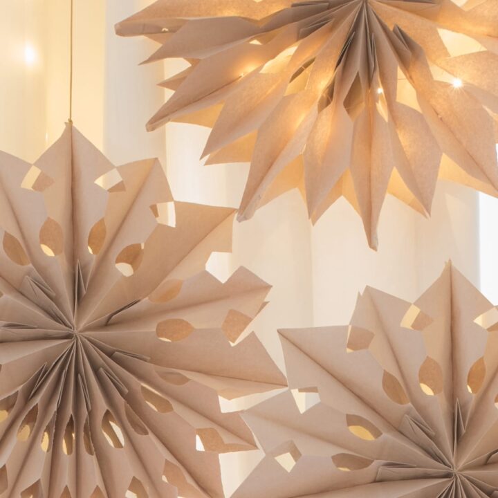 three finished paper bag snowflakes with fairy lights