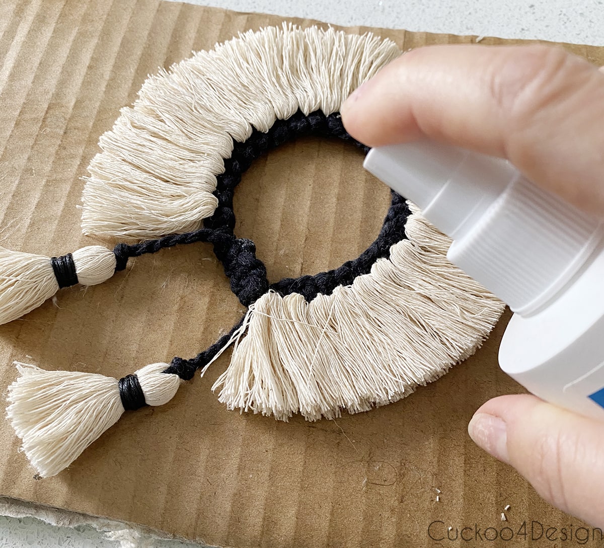 spraying the fringed part of the knotted bracelet with fabric stiffener