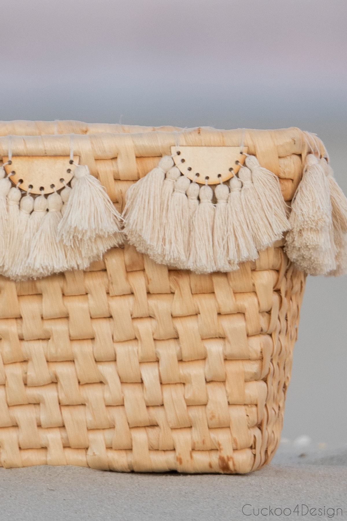 tassel embellishment on a basket that is sitting on the beach
