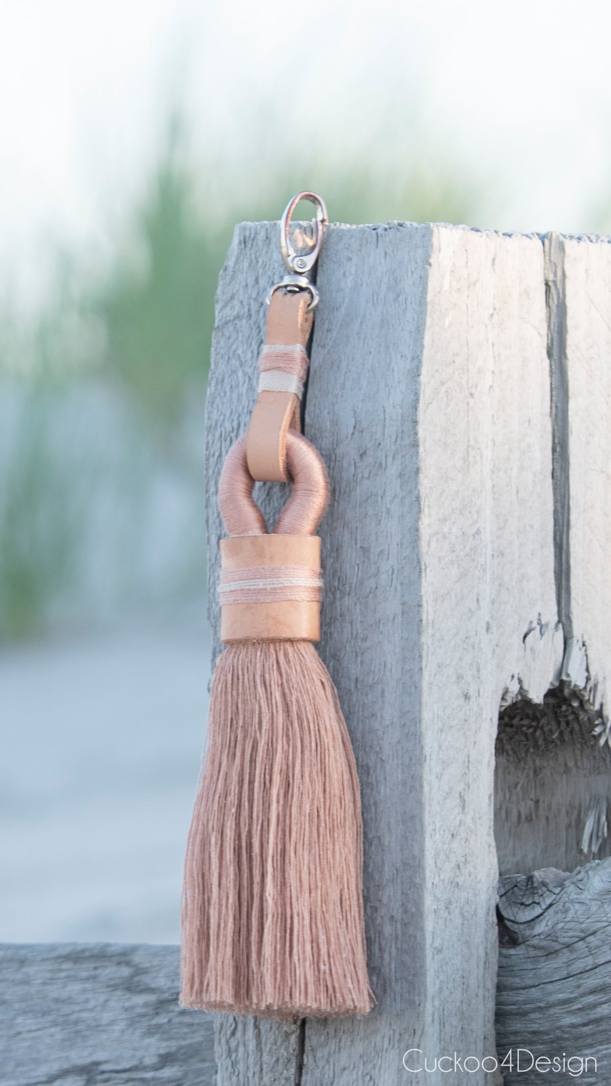 stylish tassel keychain hanging on beach fence