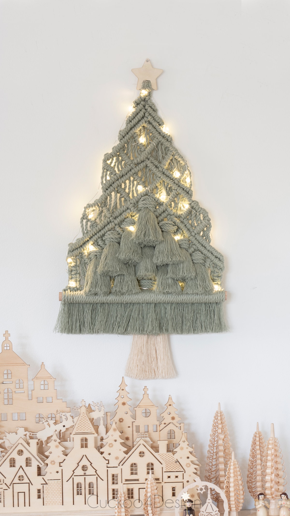 macrame Christmas tree above wooden Christmas village and fairy lights 