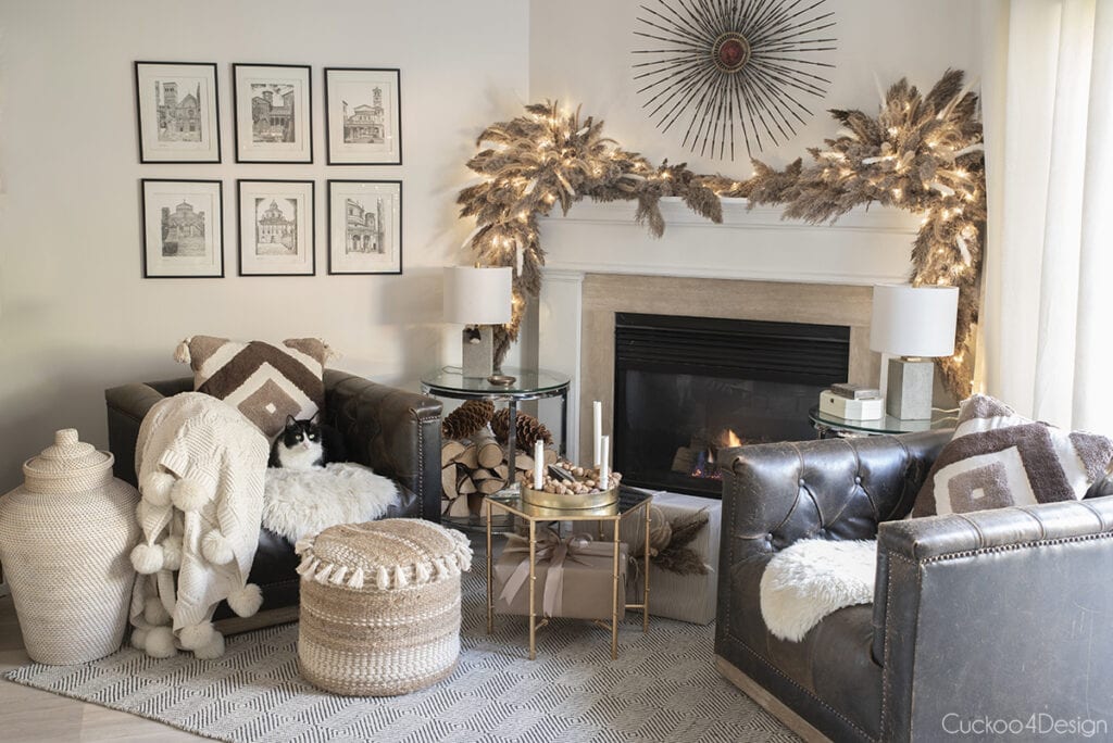 fireplace area with pampas grass garland, leather swivel chairs and neutral pillows and throws 