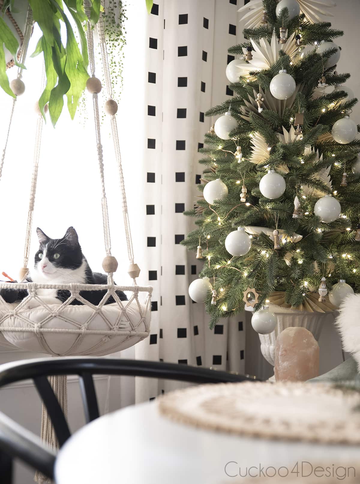 cat in hanging macrame cat bed next to Christmas tree
