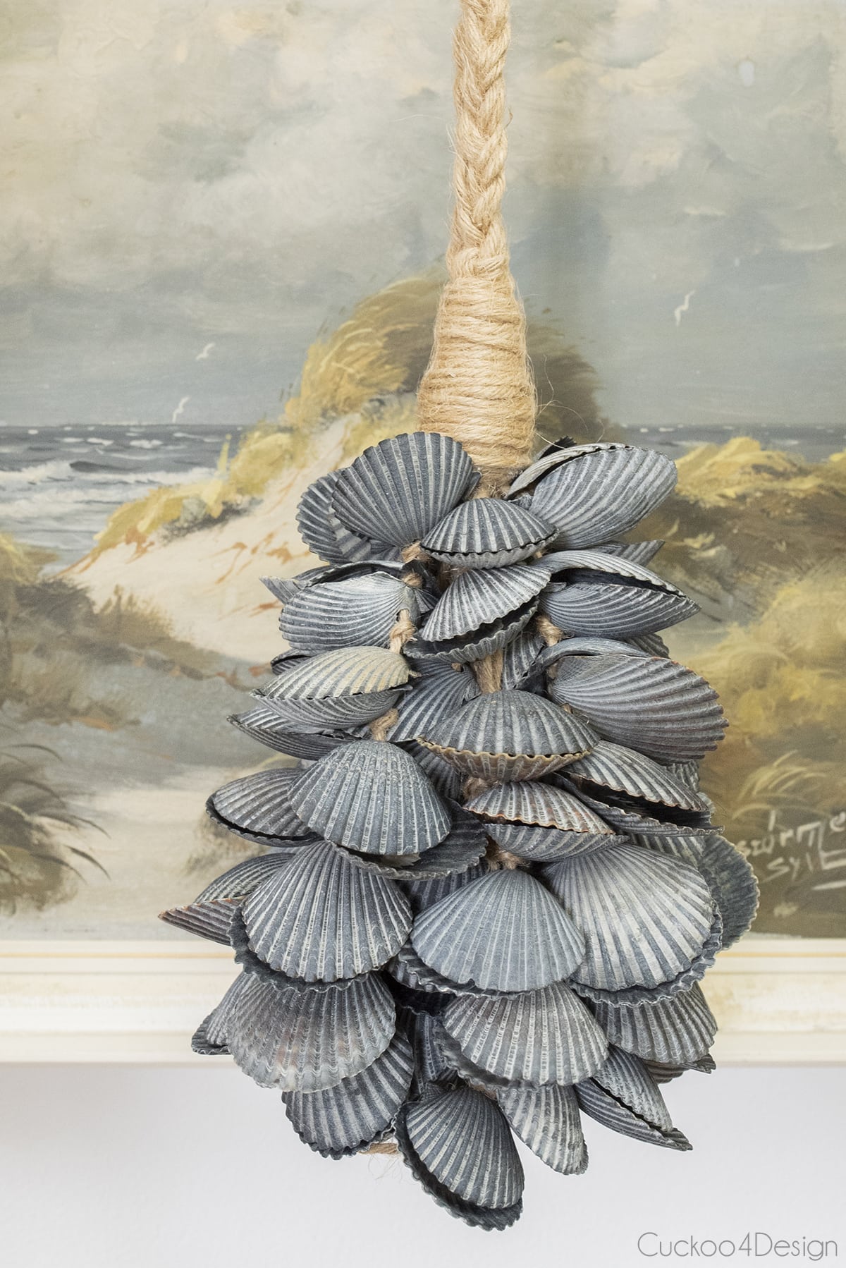 seashell tassel made of black bay scallop seashells in front of ocean painting