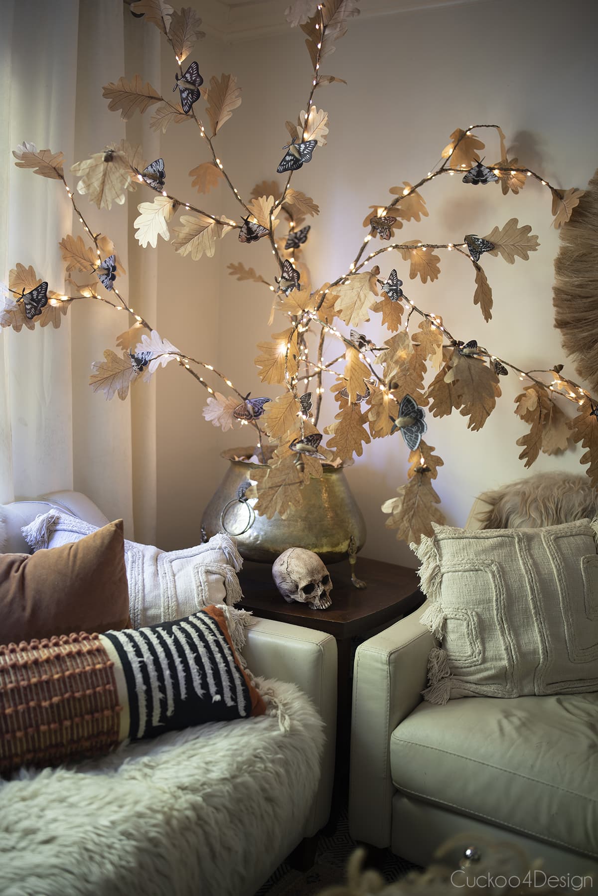 full living room view with paper moths clipped on lit branches and skull on sidetable