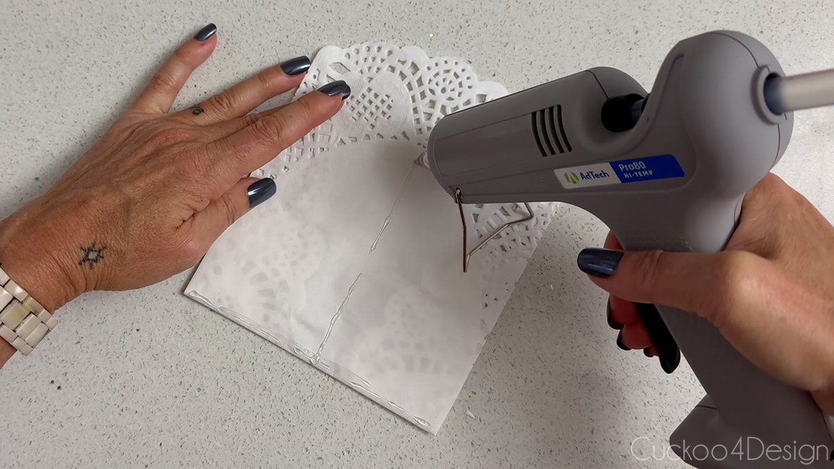 applying a thin T-shaped line of hot glue to outside of folded doily