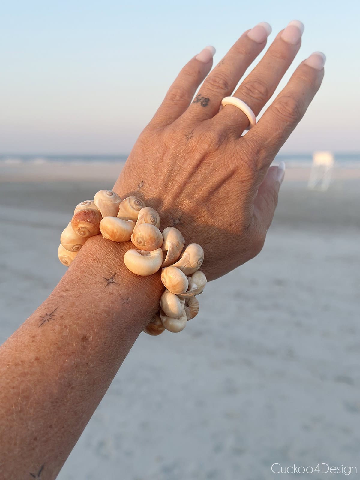 wearing the finished snail shell bracelet on my wrist while on the beach