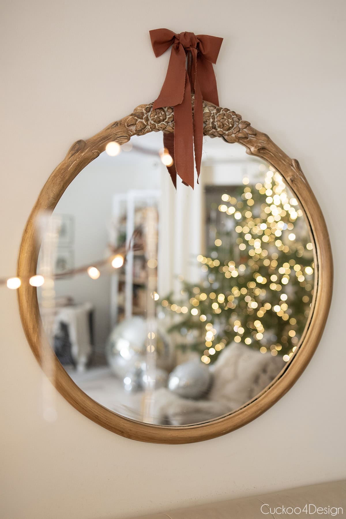 gold round mirror with bow and view of Christmas tree