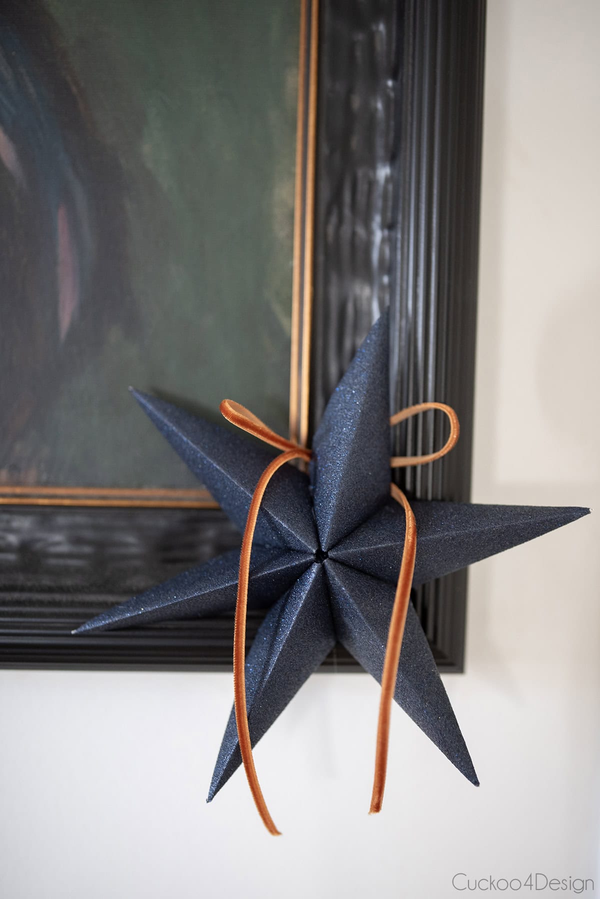 close up of blue glitter folded paper star with bow on picture frame