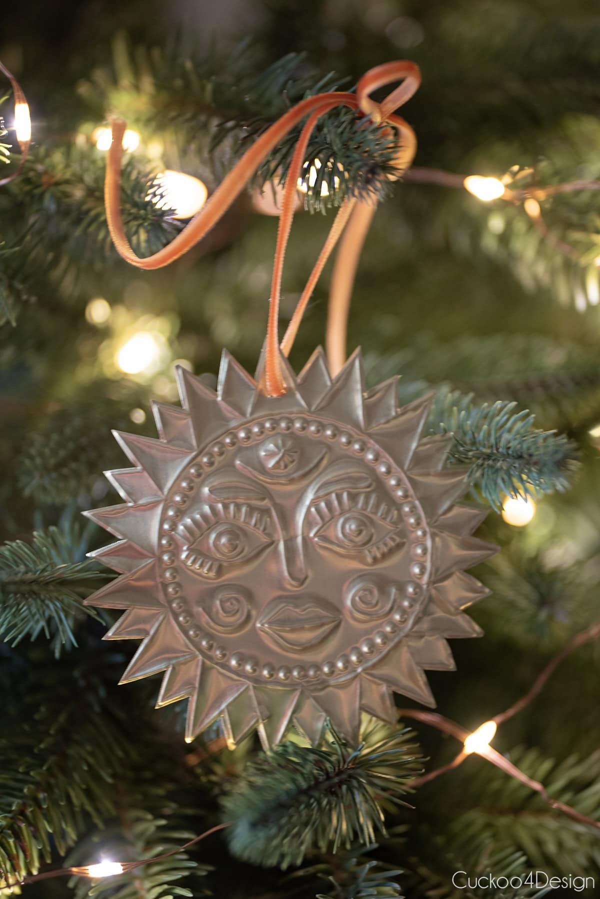 close-up of embossed tin sun ornament hanging in a Christmas tree