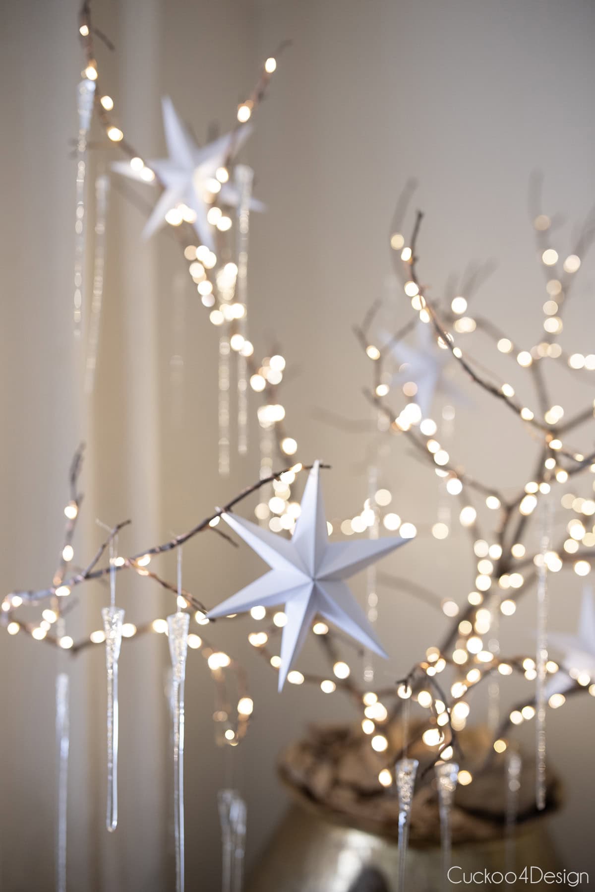 several folded paper stars hanging on lit branches