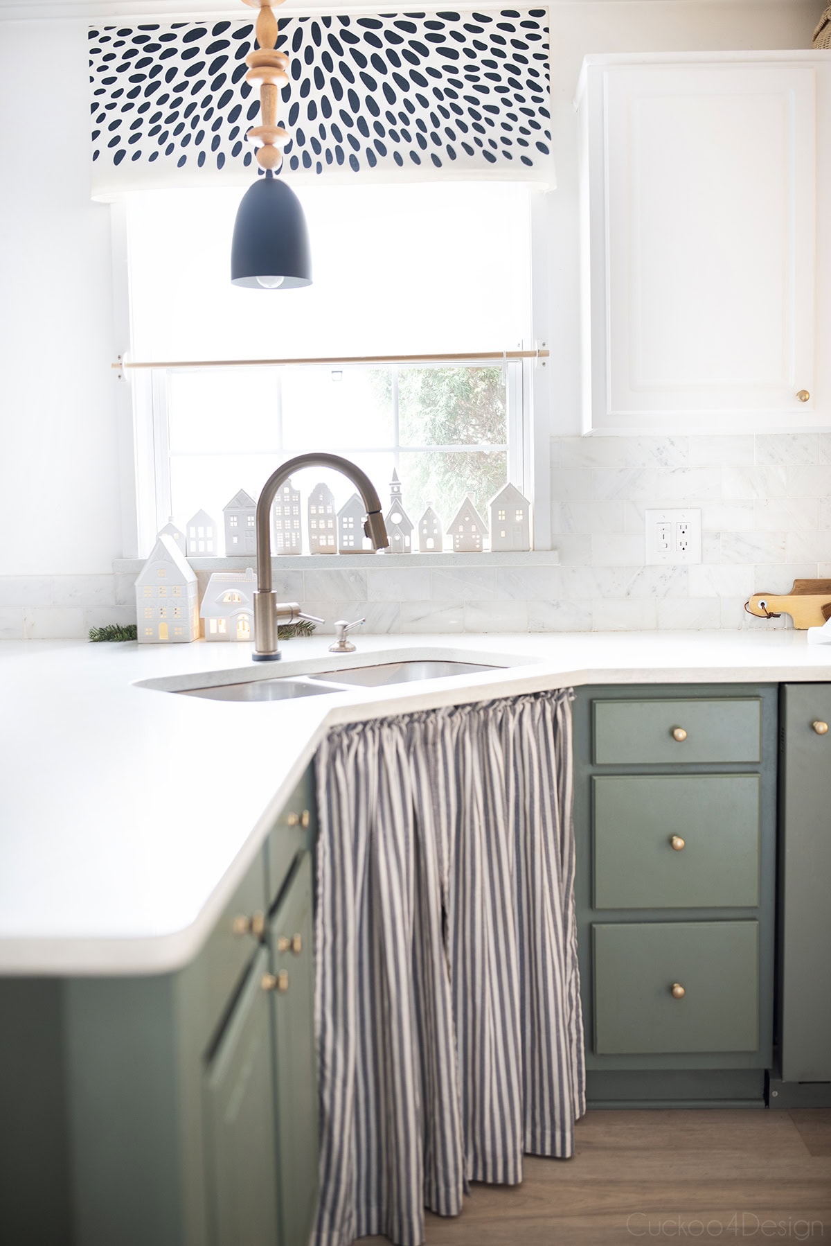 green kitchen with white ceramic houses in kitchen window
