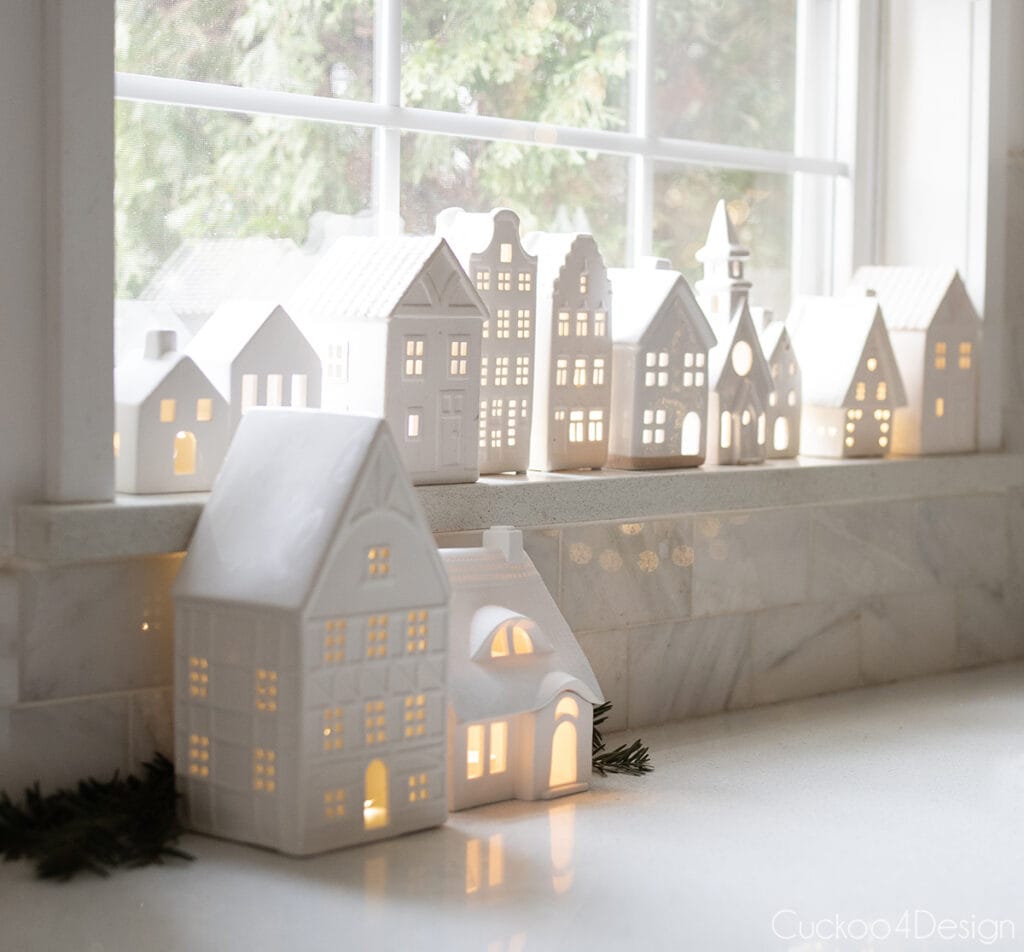 close-up of white ceramic houses in kitchen window