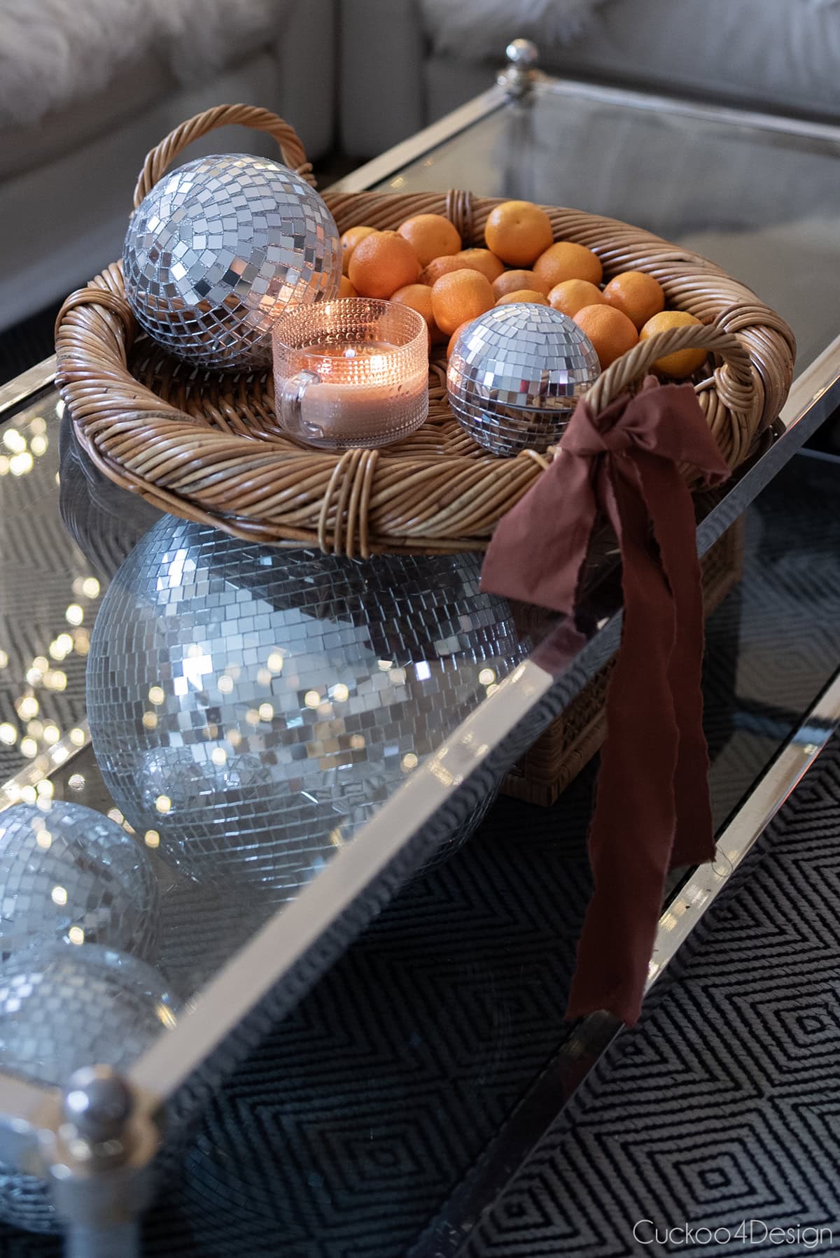 two-tier coffee table with basket tray, disco balls, candle, and cutie oranges