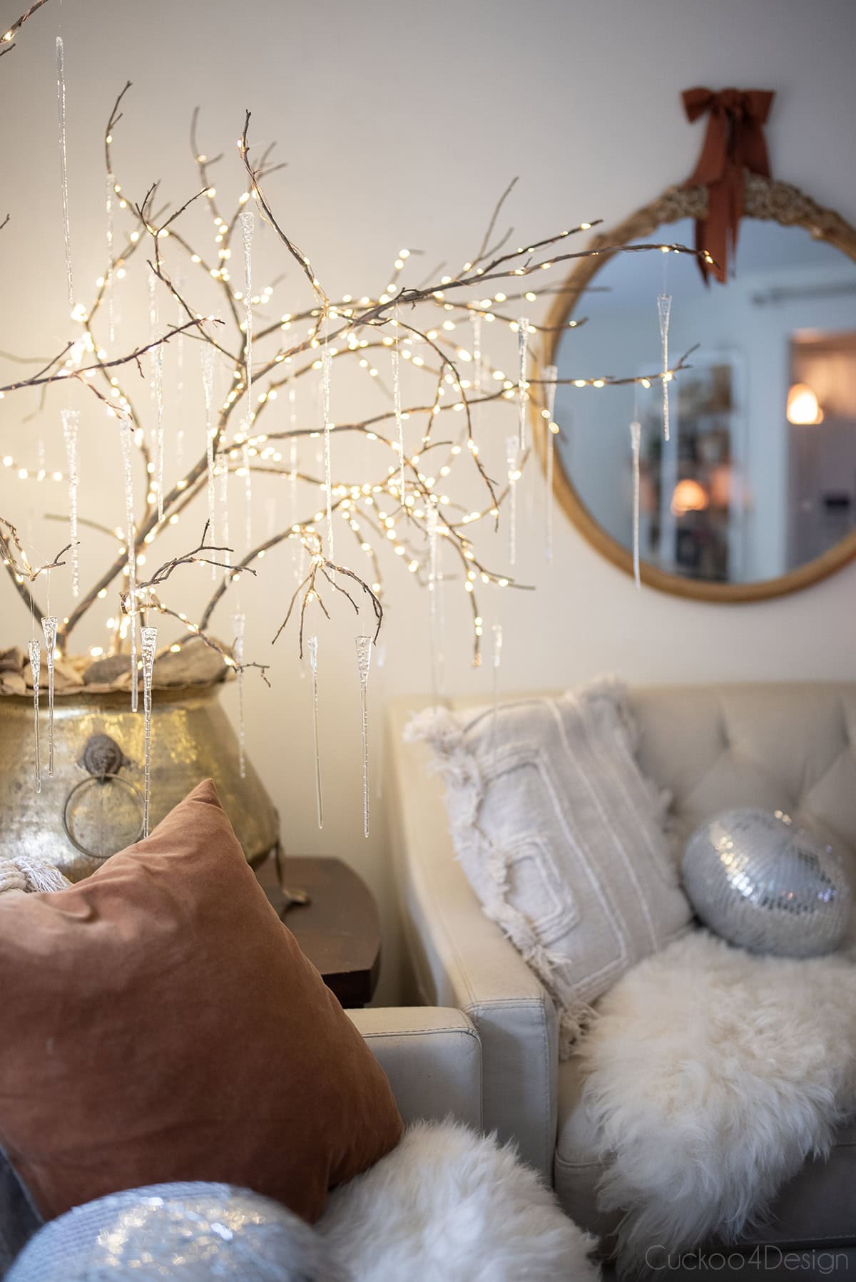 disco ball pillows on sofa with icicle lit branches on table in living room