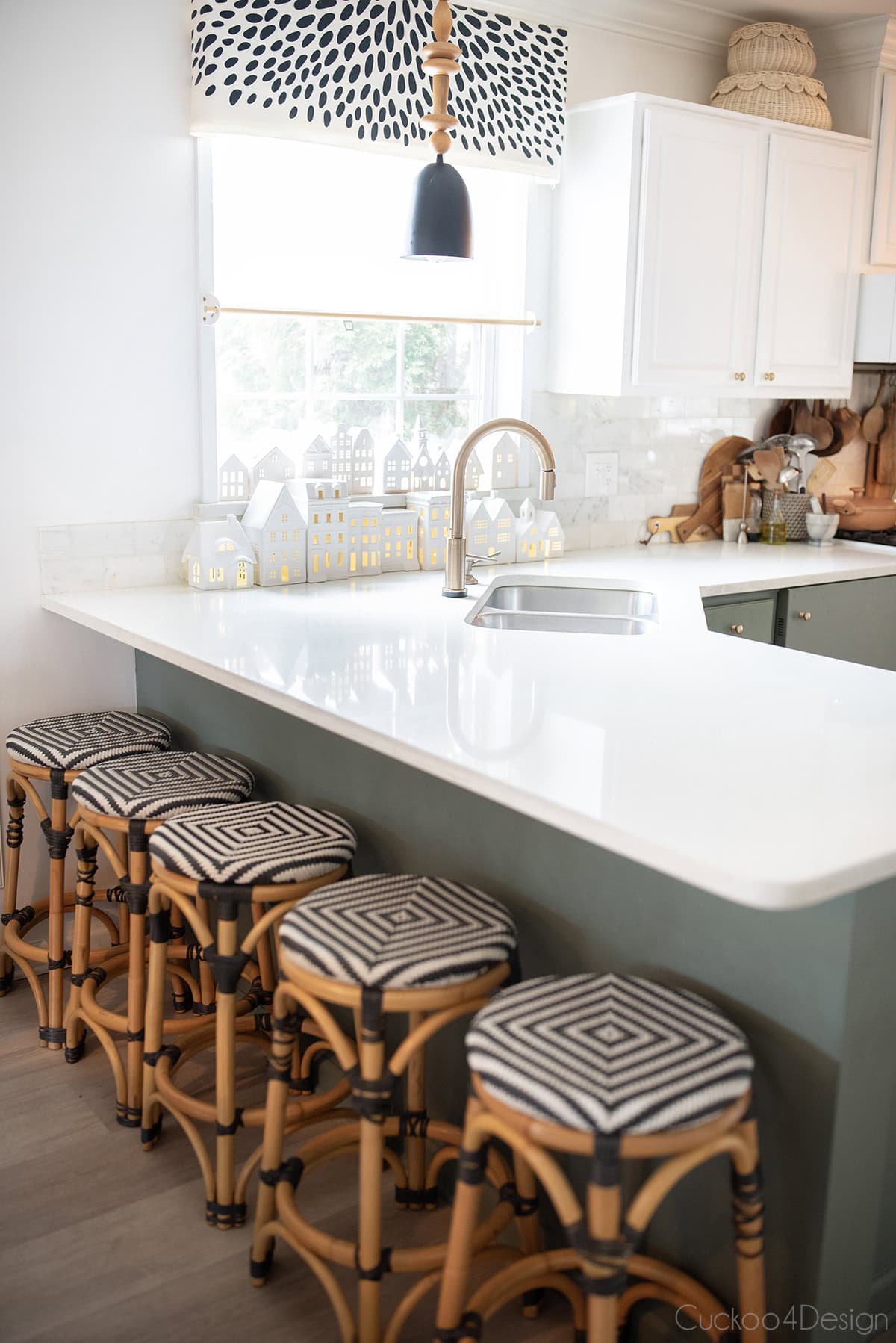 white ceramic houses in kitchen window with white countertops and green cabinets