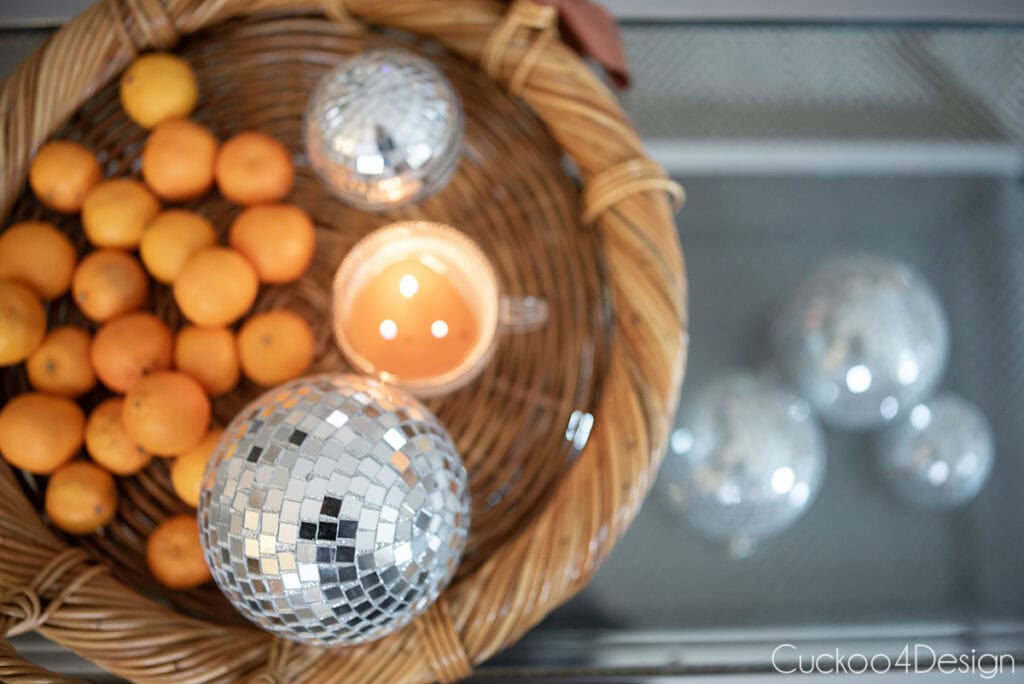 top view of basket tray on coffee table filled with disco balls, cutie oranges, and disco balls