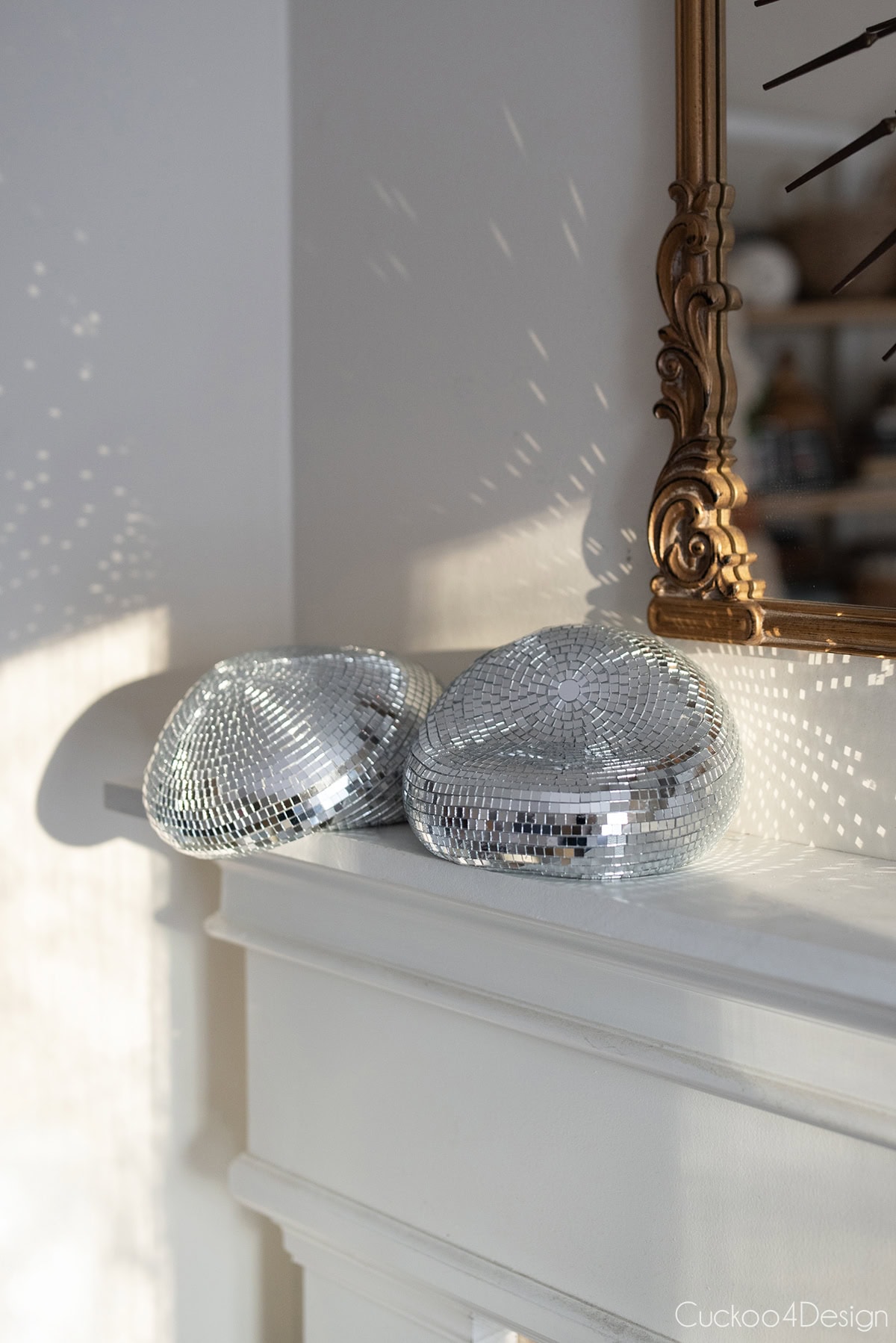 two finished DIY melted disco balls on fireplace mantel with gold mirror
