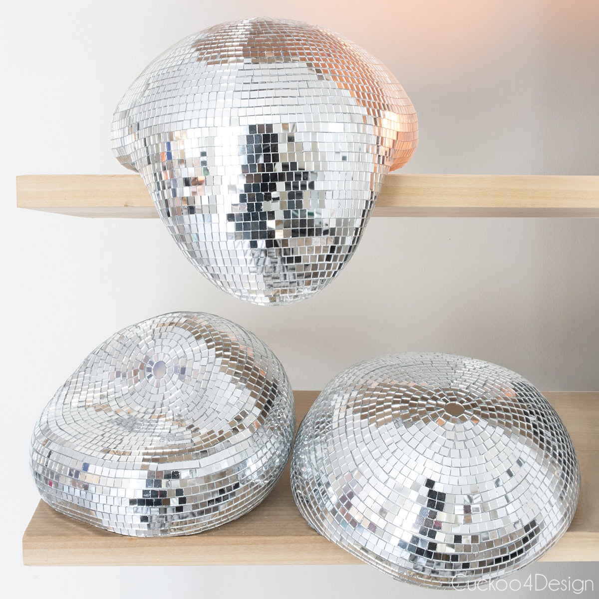 three melted disco balls sitting on wooden shelves