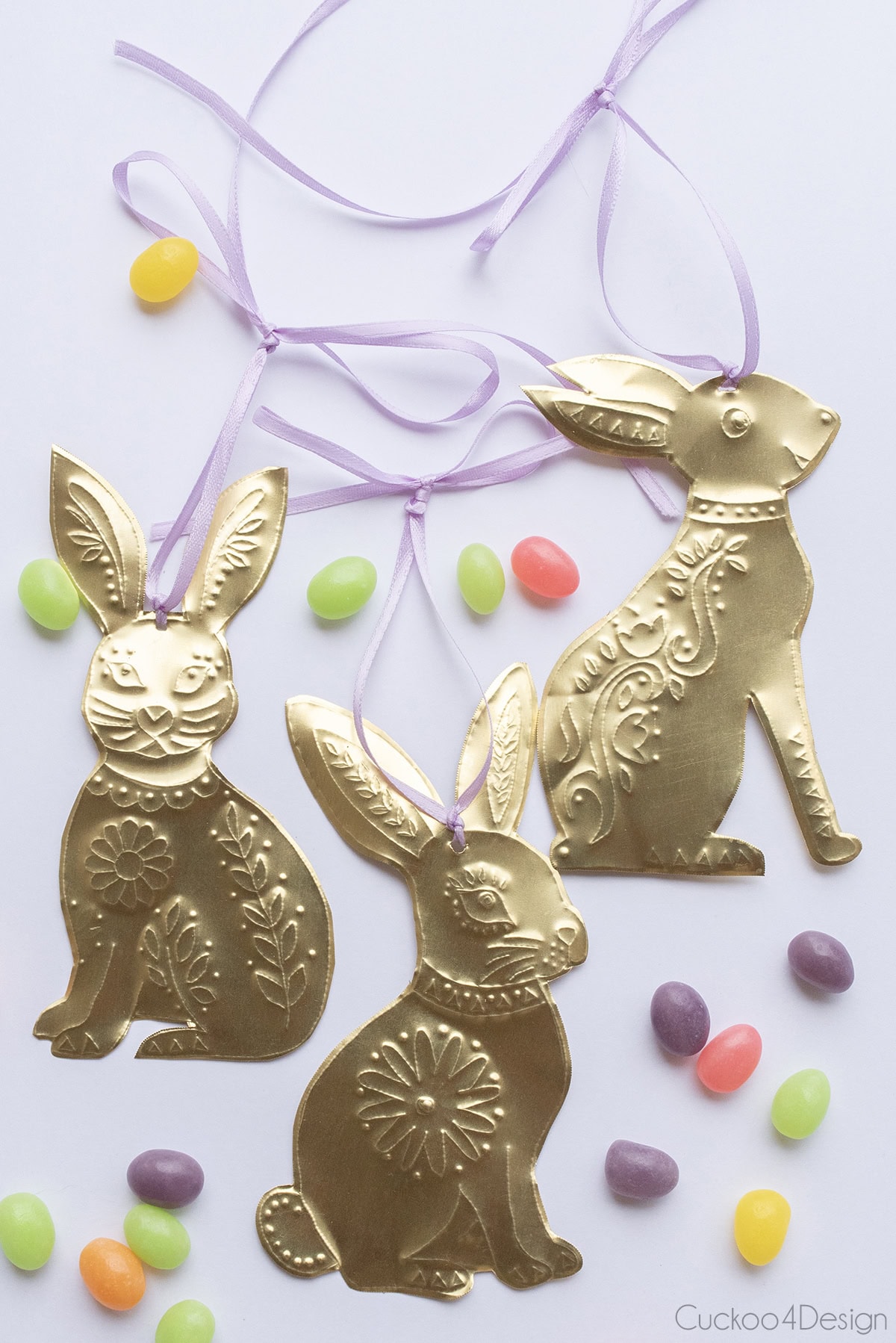 three metal DIY bunny ornaments surrounded by pastel colored jelly beans
