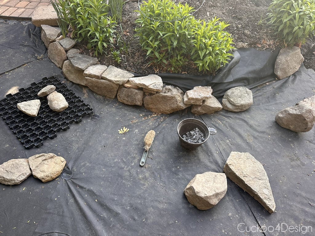 adding rocks over landscape fabric to create flower bed edging