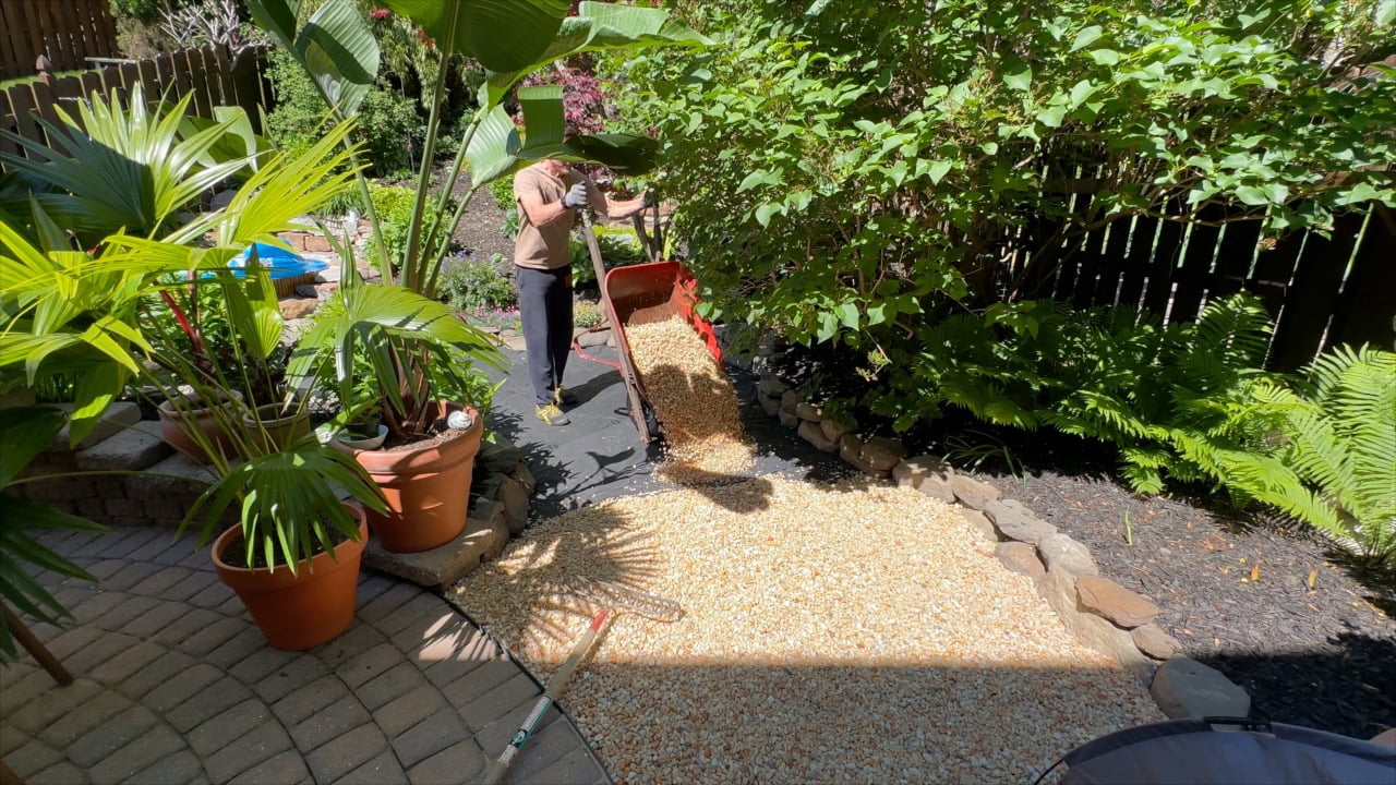 dumping gravel onto landscaping fabric with wheelbarrow