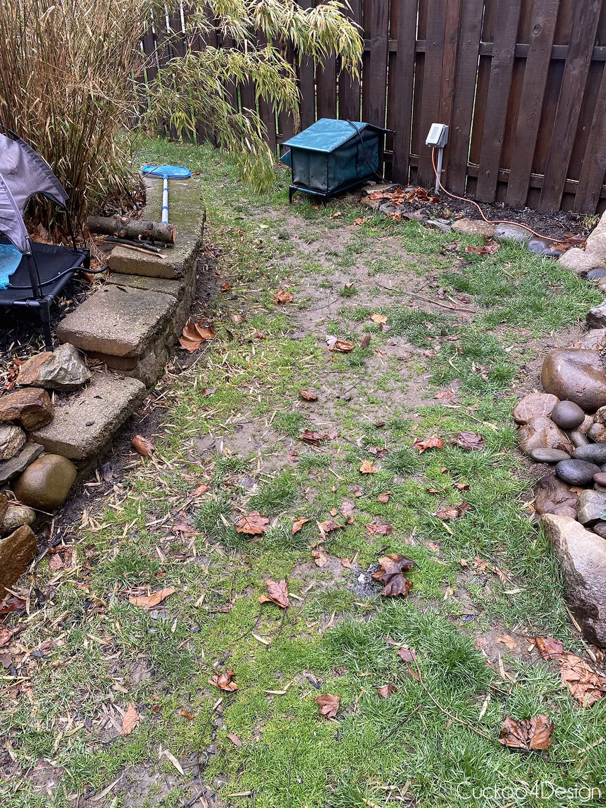 muddy backyard area with poor drainage and patchy grass before replacing with pea gravel