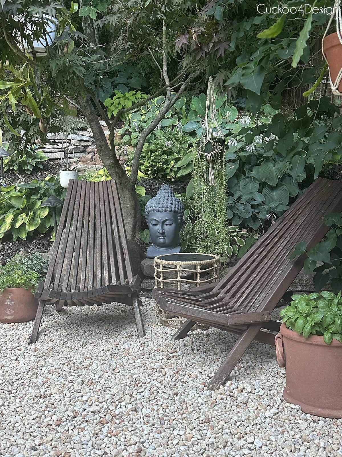 teak chairs on gravel iwth buddha head and plants