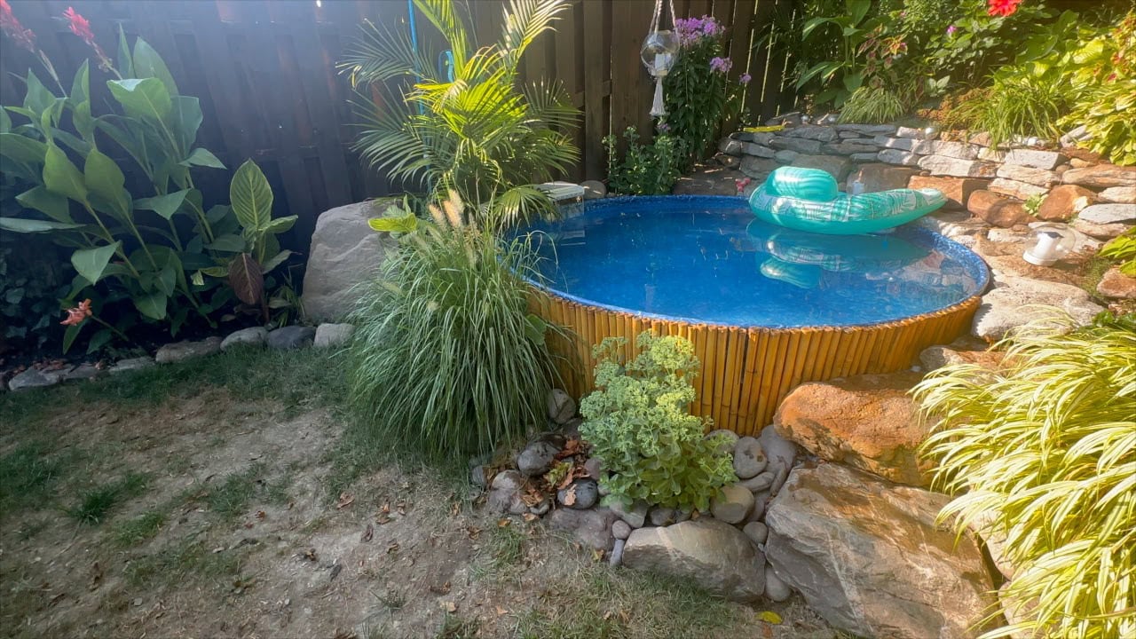 patchy grass area and dry dirt in backyard around stock tank pool