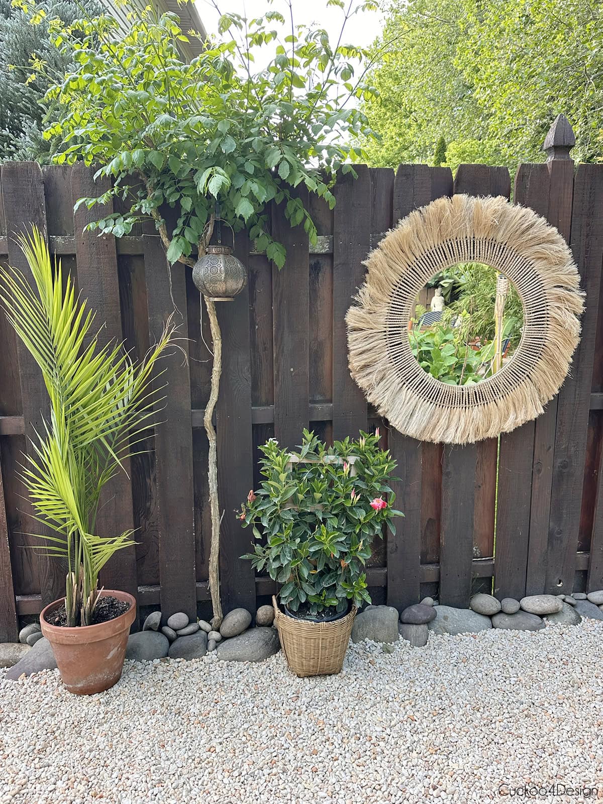 view of fence with mirror hanging on fence and a trumpet vine tree growing on fence