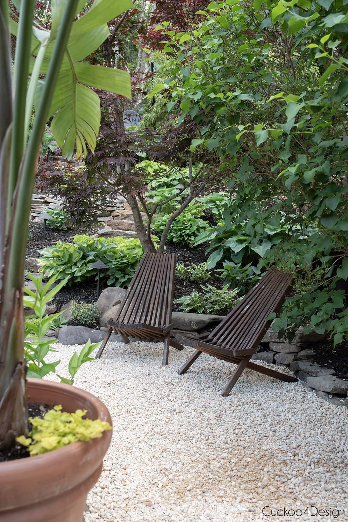 view of small seating area on pea gravel under a lilac bush