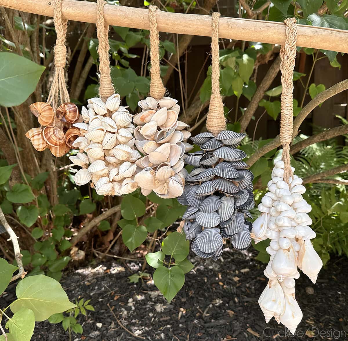 five different seashell tassels hanging on a wooden stick