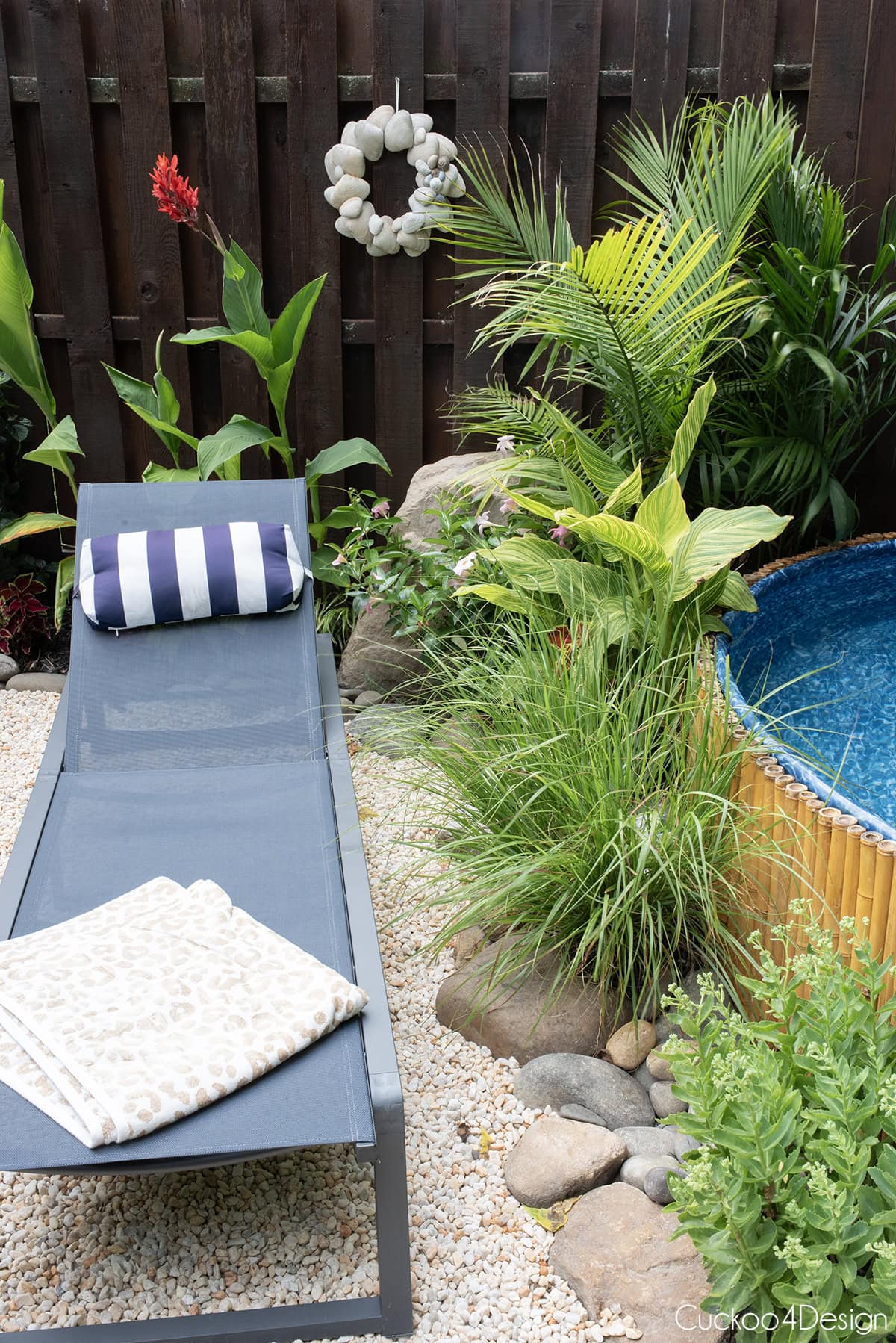 DIY seashell wreath hanging above plants on a wooden fence be a stock tank pool