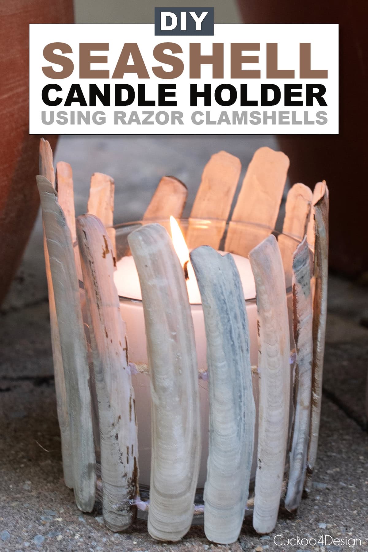 DIY seashell candle holder made with razor clamshells glued to jute yarn around a glass and lit candle inside
