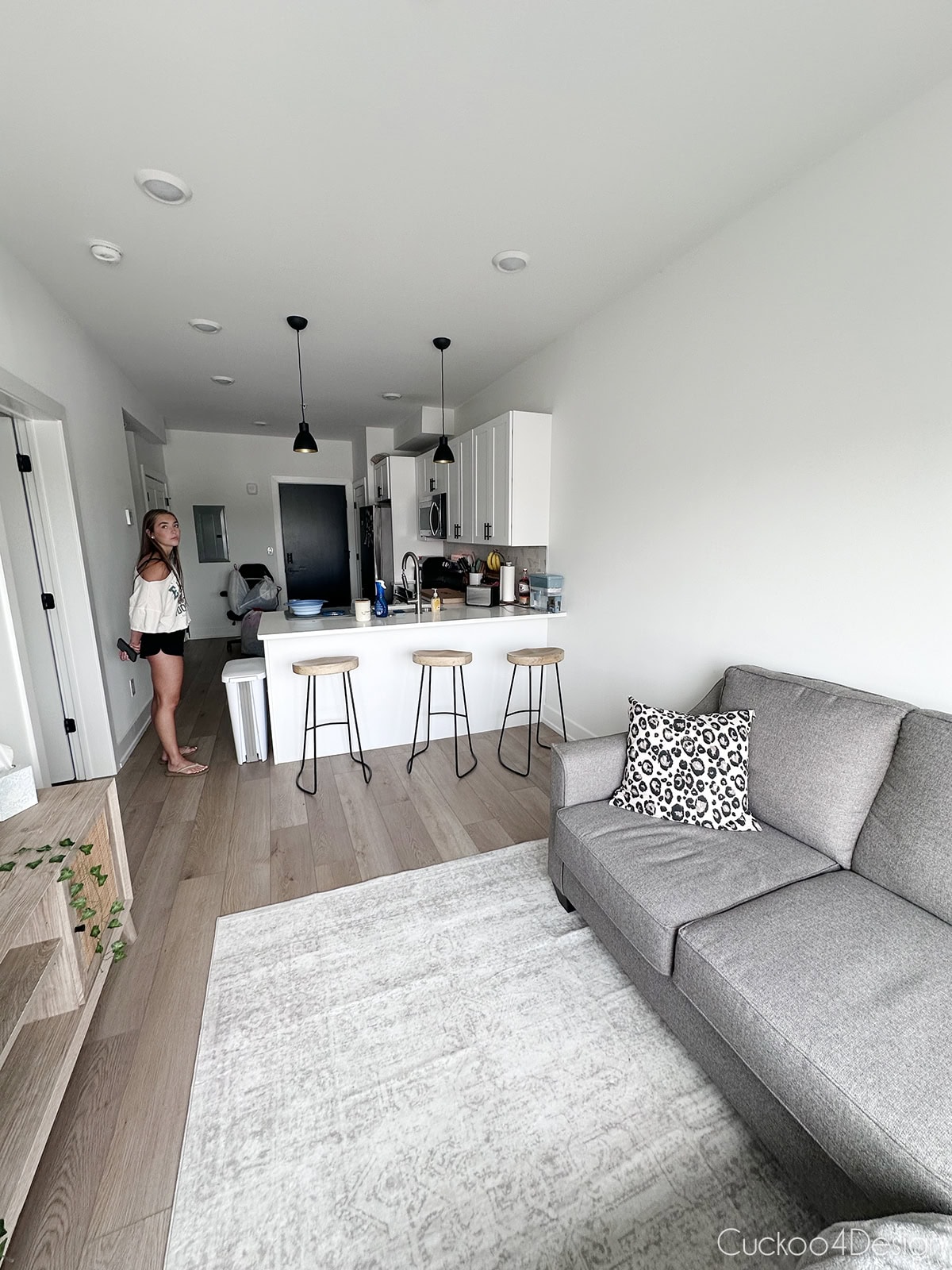 living room with a gray sectional, wood counter stools, and open kitchen in a one bedroom Philadelphia apartment