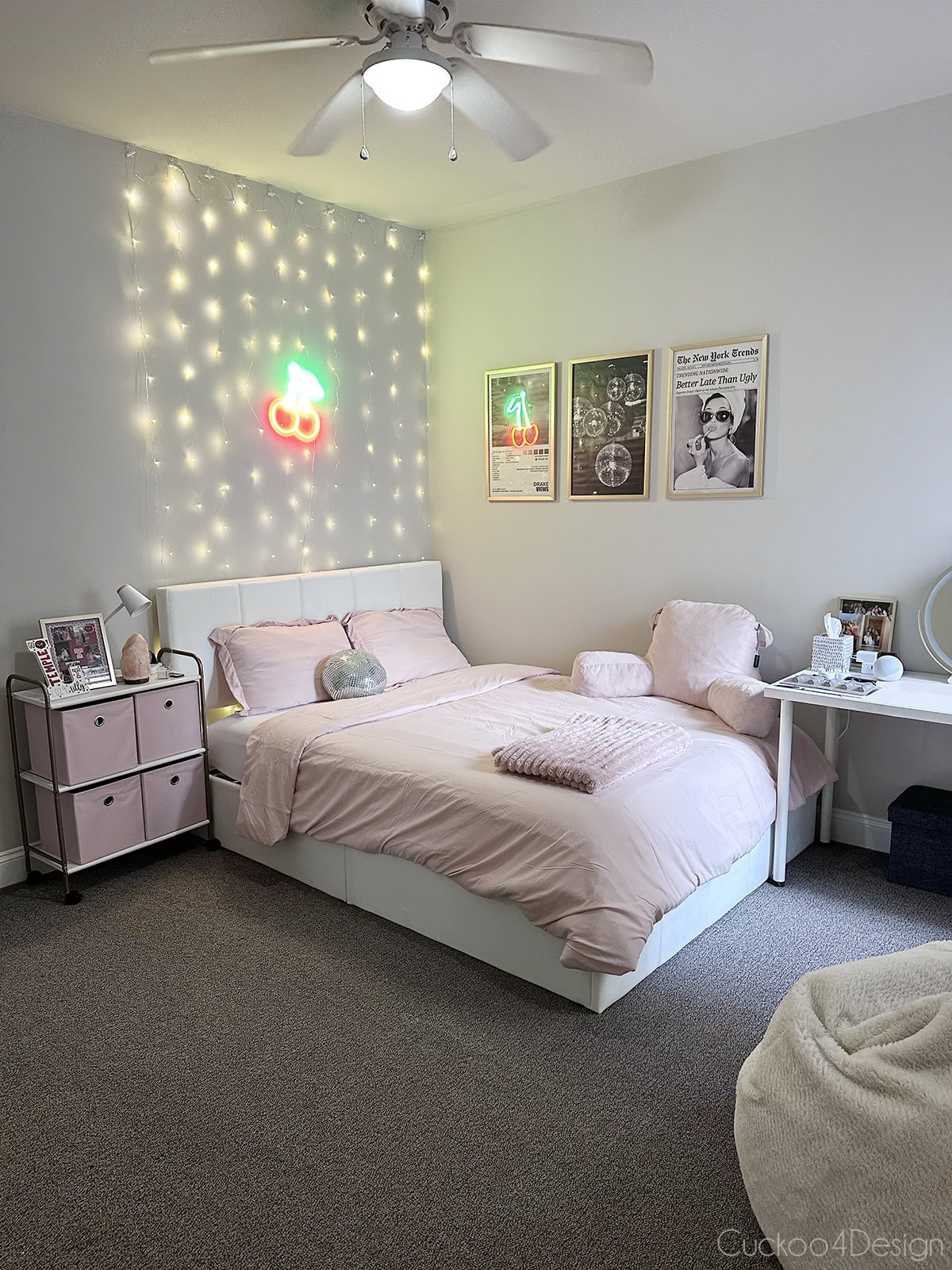 queen-sized white velvet lift-up hydraulic storage bed in decorated college apartment bedroom with pink accents and fairy lights