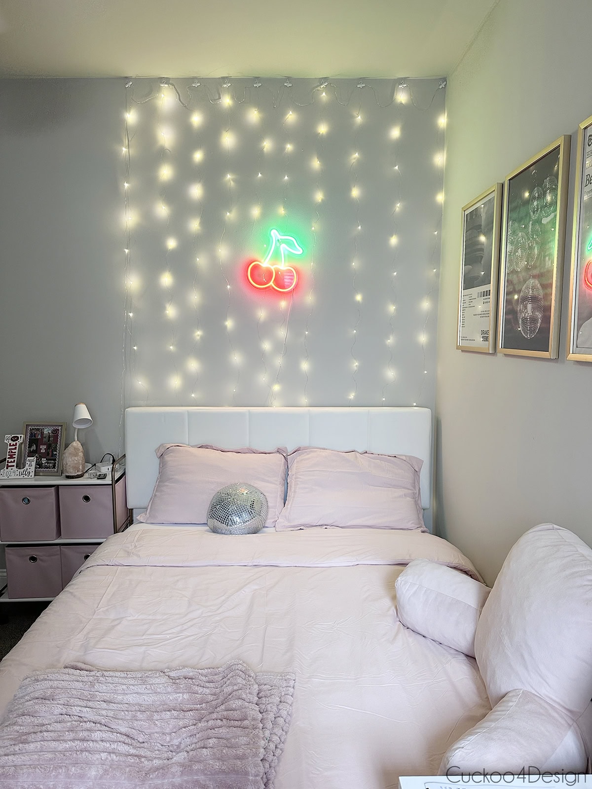 front view of queen-sized white velvet lift-up hydraulic storage bed in decorated college apartment bedroom with pink accents and fairy lights