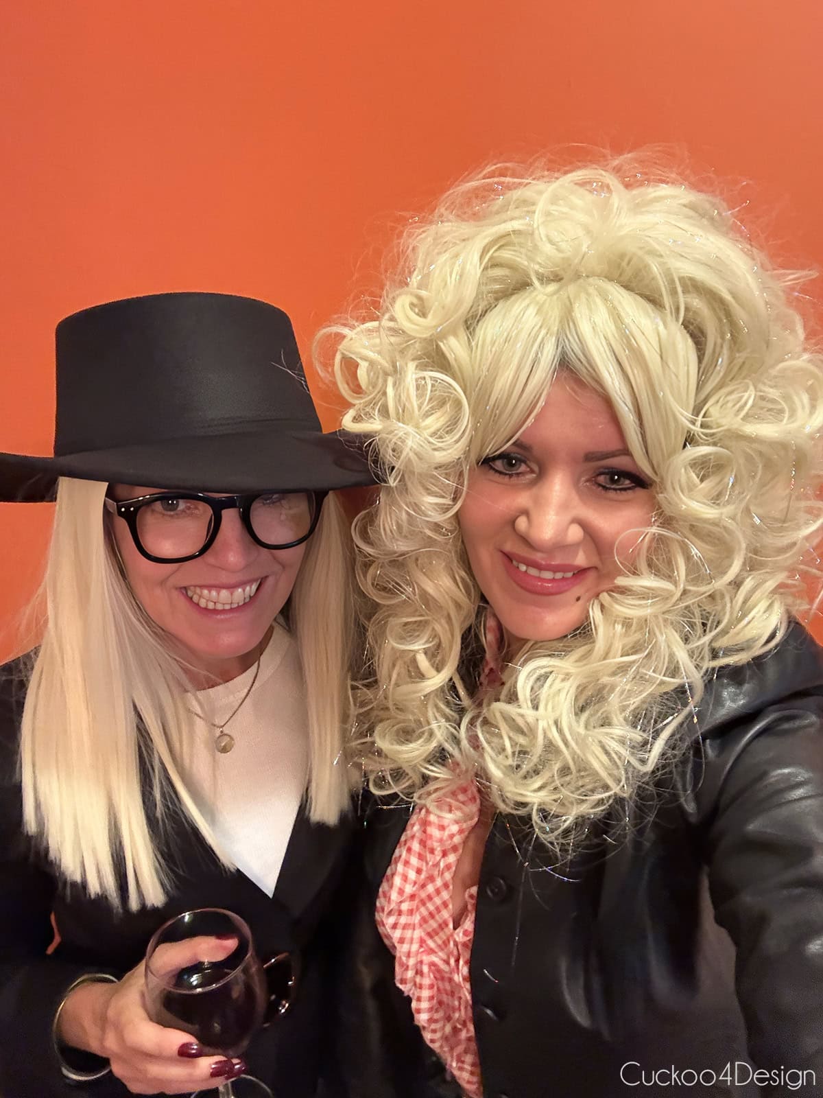 selfie of a Diane Keaton costume and a Dolly Parton costume at a Halloween party with an orange wall behind them