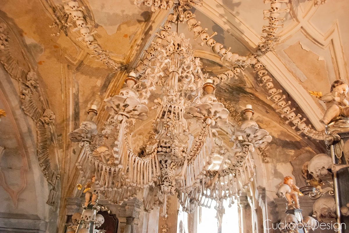 Bone chandelier and skull garlands on the ceiling of the Sedlec Ossuary, with cherubs on candelabras below