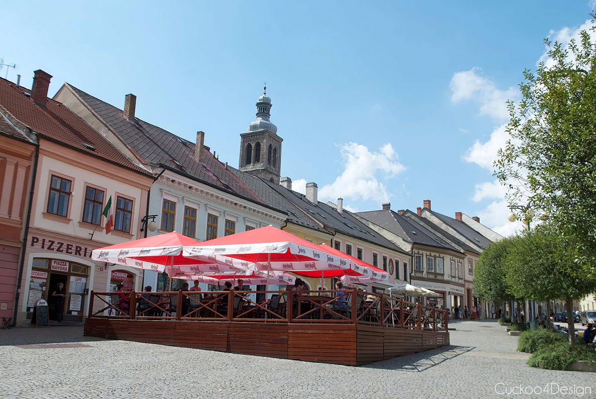 Café terrace with red umbrellas on a square lined with colorful houses in Kutná Hora’s old town