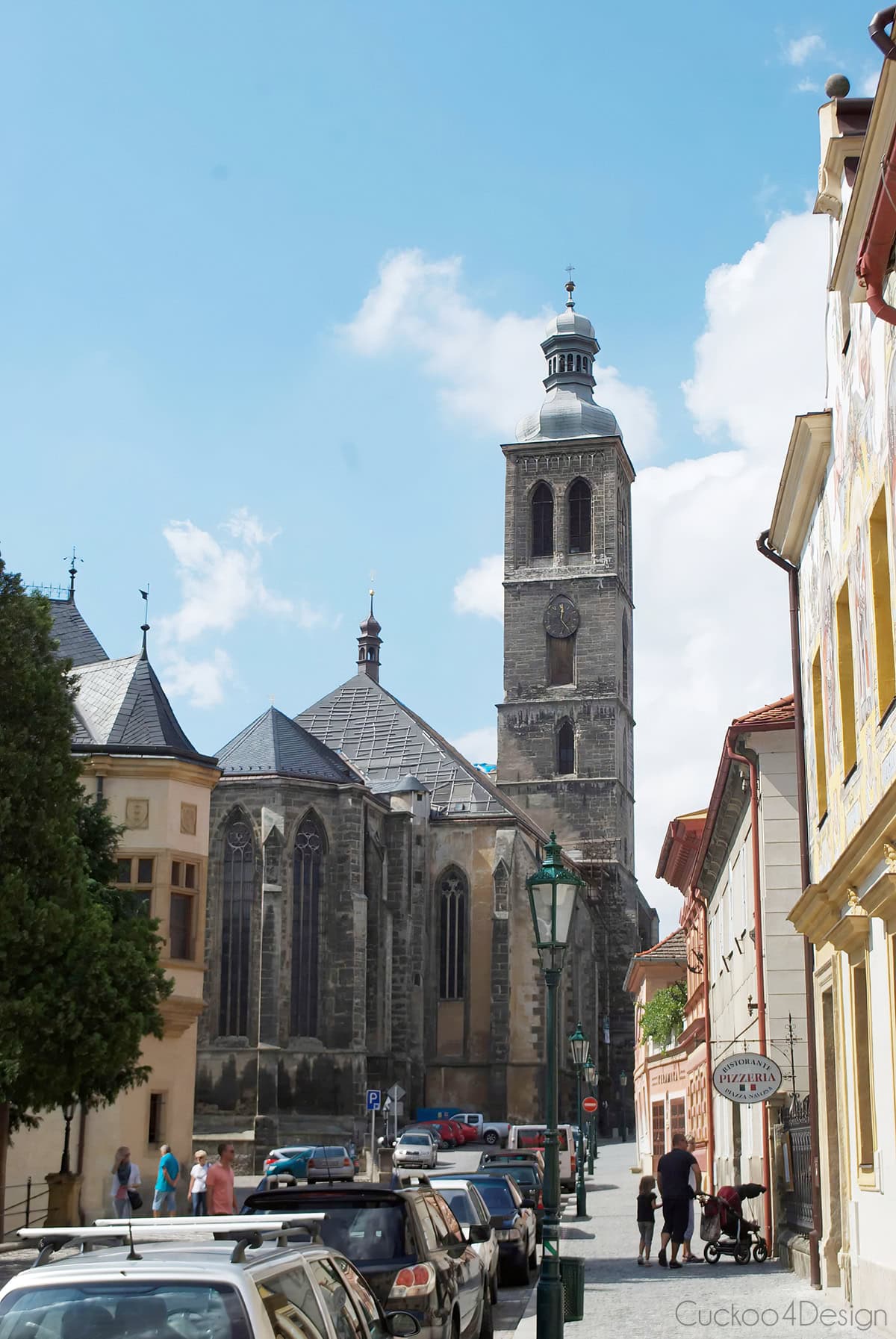Gothic St. James Church with its tall stone tower, seen from a street in Kutná Hora