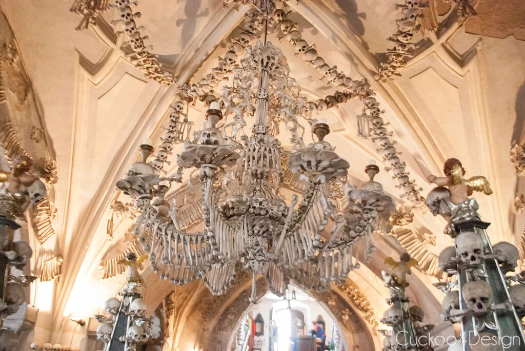 The bone chandelier hanging in the center of the Sedlec Ossuary, surrounded by skull garlands and cherubs on bone candelabras